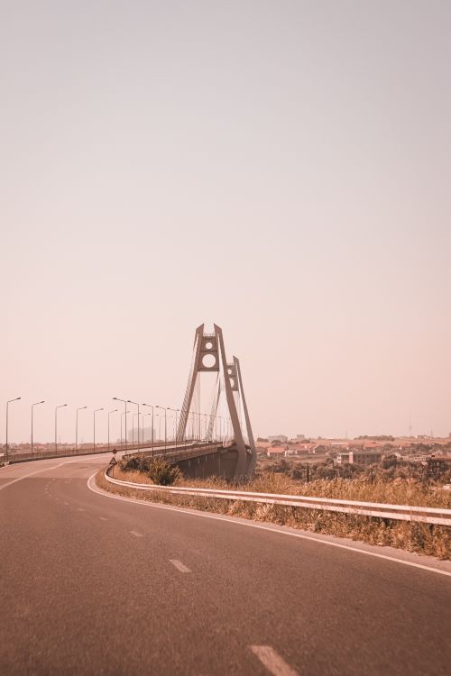 Free A modern bridge extending over a road under a clear, warm sky highlighting architectural design. Stock Photo