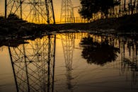 日落时，发电塔的剪影倒映在水坑中，形成工业场景