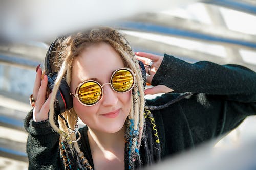 Free Woman with Dreadlocks Listening to Music on her Headphones Stock Photo