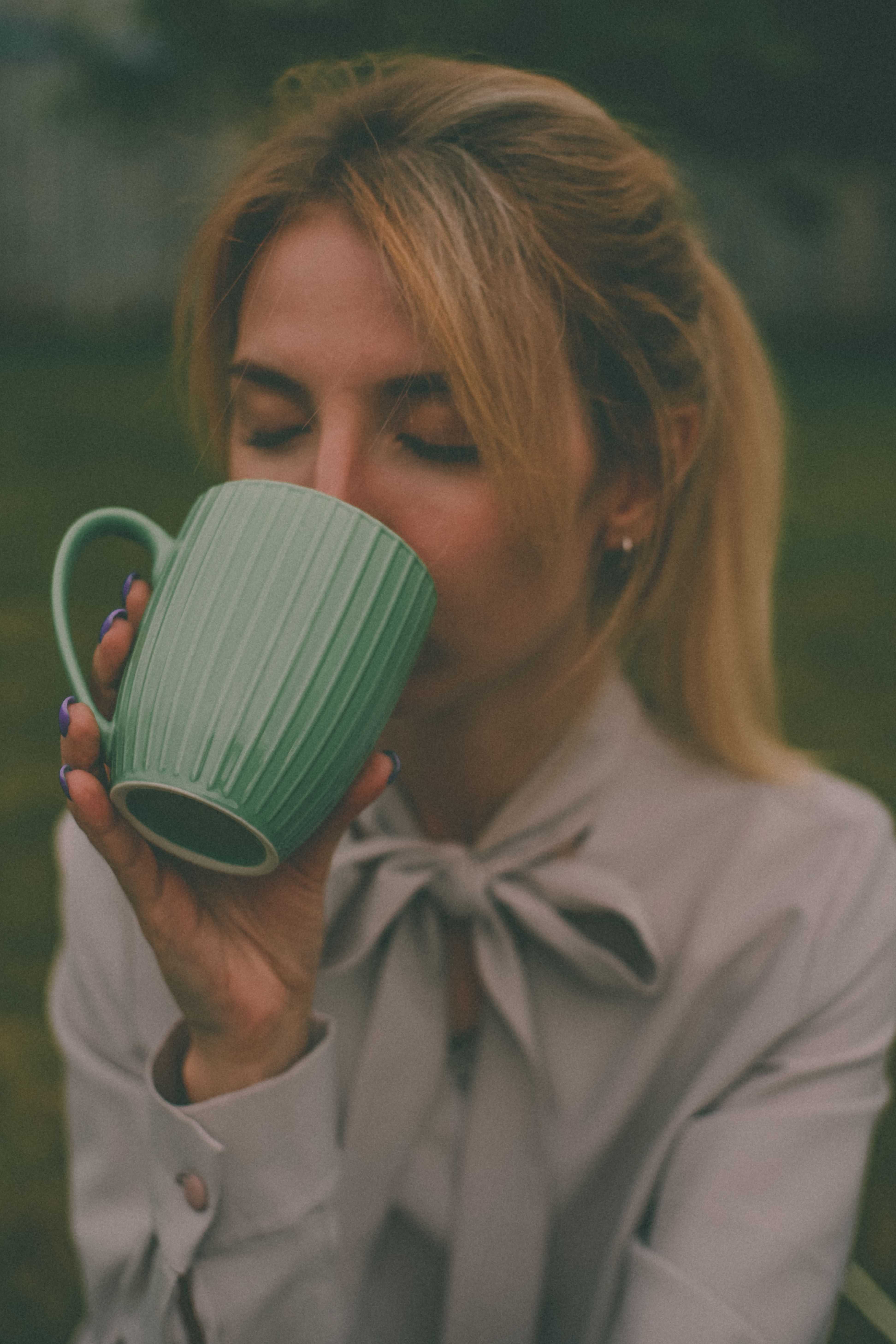 A peaceful moment of a woman savoring a drink with closed eyes, capturing tranquility.