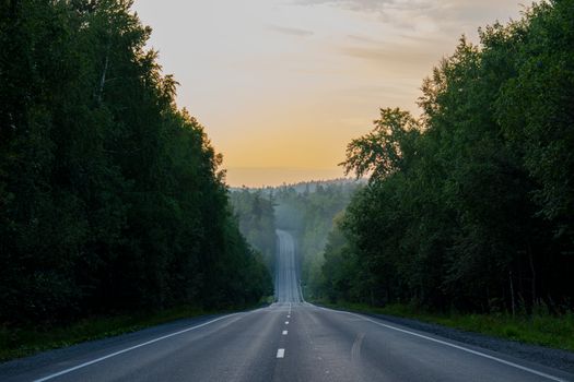 Peaceful road through lush forest at sunrise near Zlatoust
