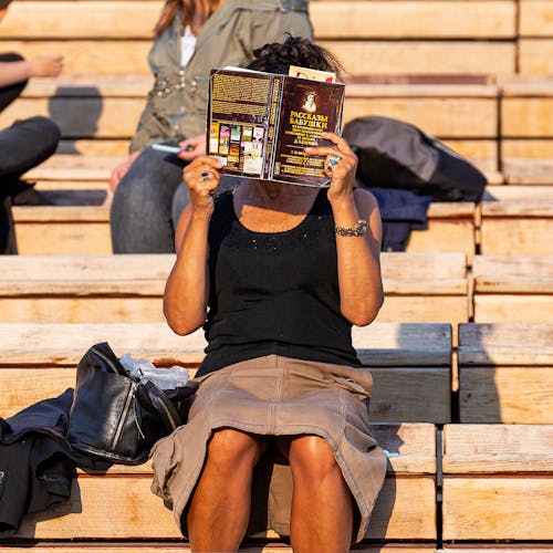 Free Woman Hiding her Face Behind Book  Stock Photo