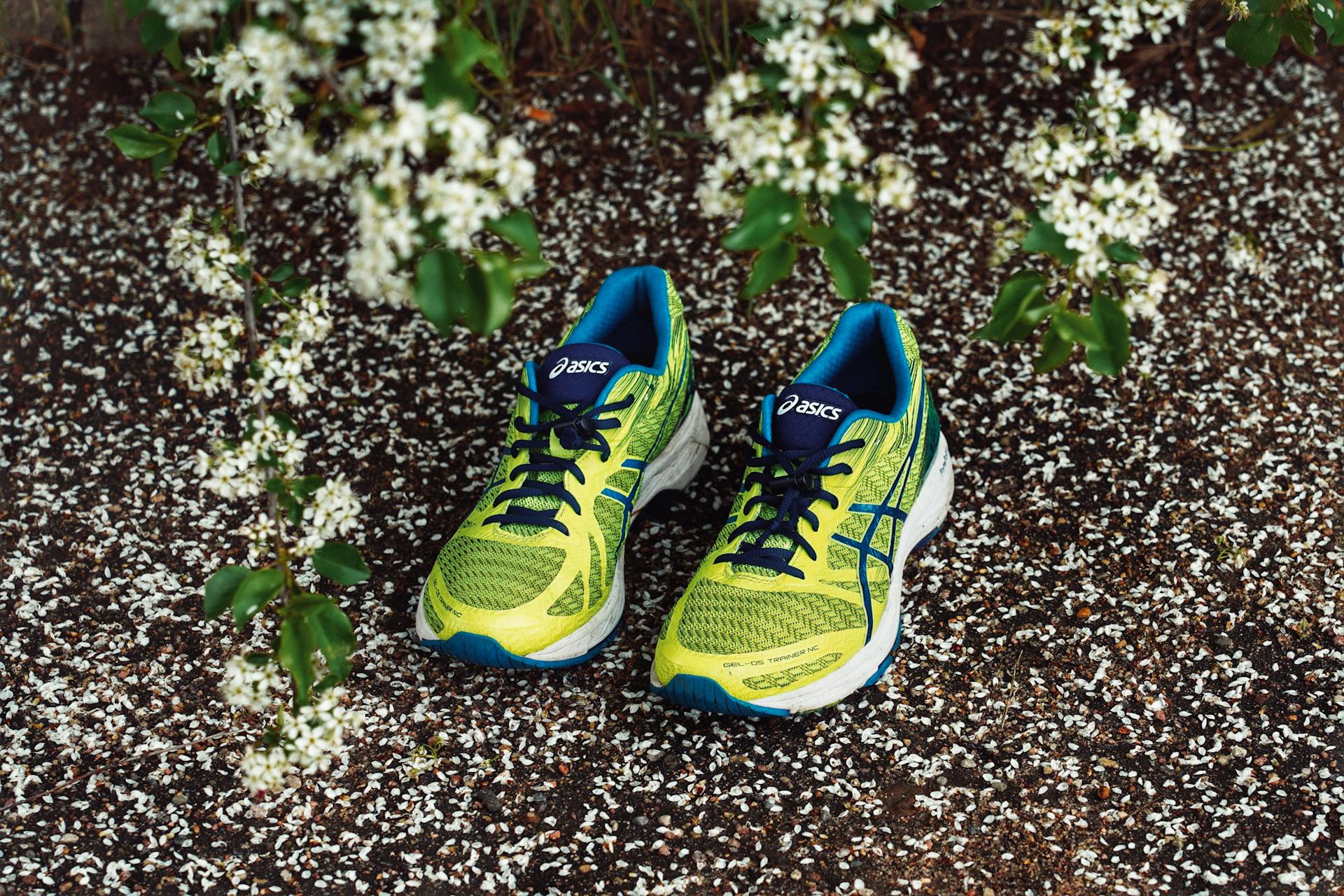 Vibrant green Asics running shoes creatively showcased on a floral background.