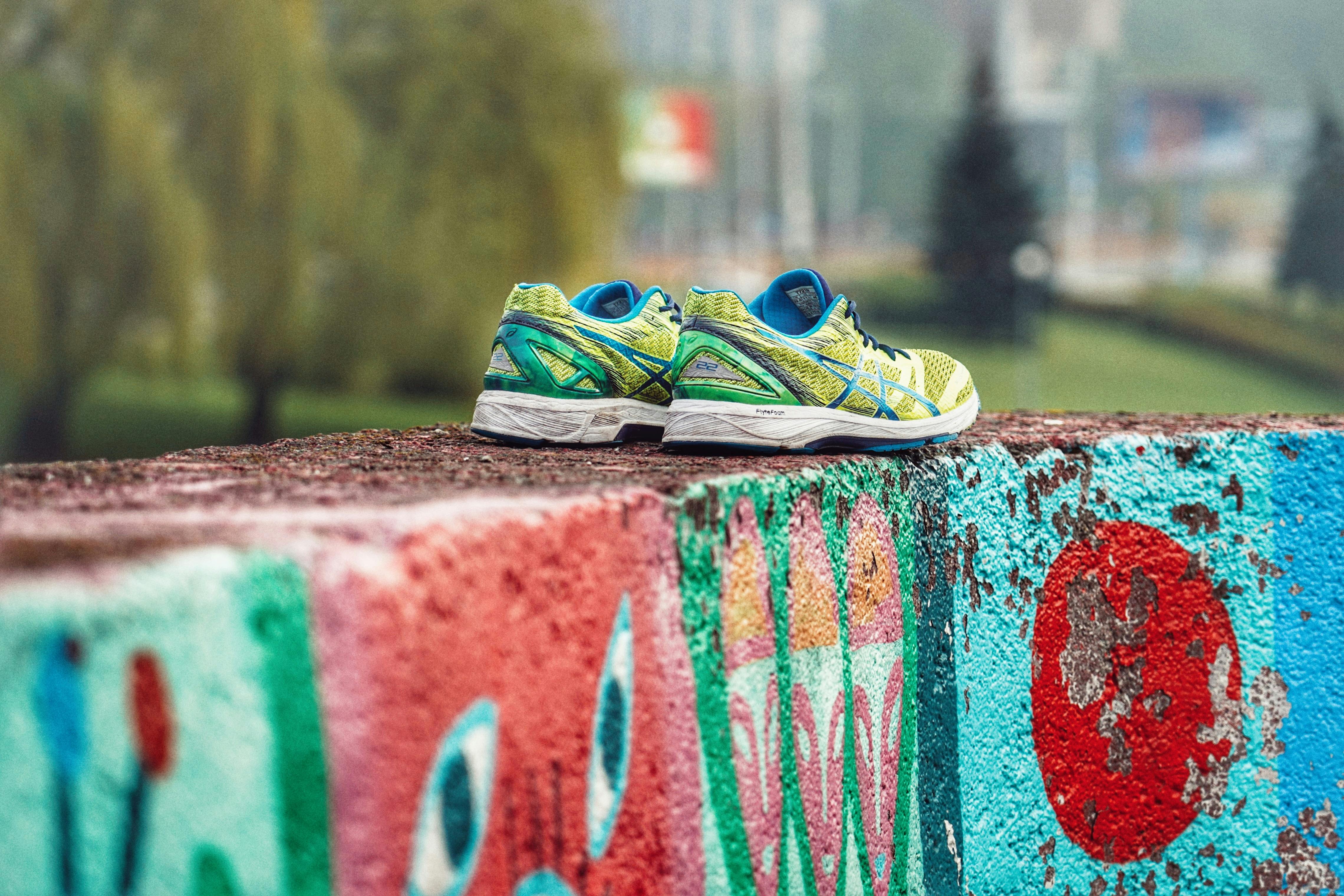 Colorful sneakers on a graffiti wall outdoors, showcasing urban art and style.