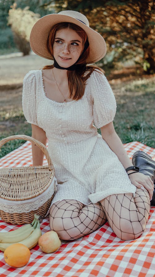 A Woman in White Dress Sitting on the Picnic Blanket