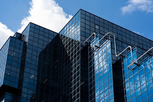 Architectural shot of a modern glass skyscraper in London with reflections of clouds and sky.