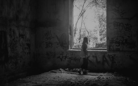 A haunting scene in an abandoned building featuring a silhouetted person and graffiti-covered walls.