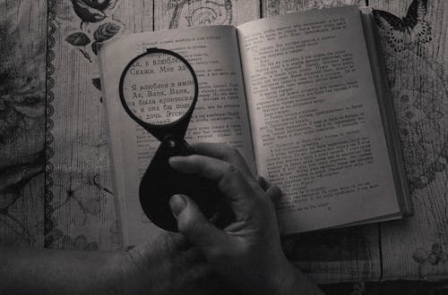 Free Person Using Magnifying Glass on Book  Stock Photo