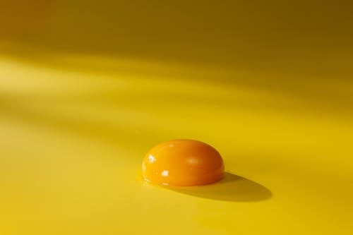 Free Egg Yolk on a Yellow Surface  Stock Photo