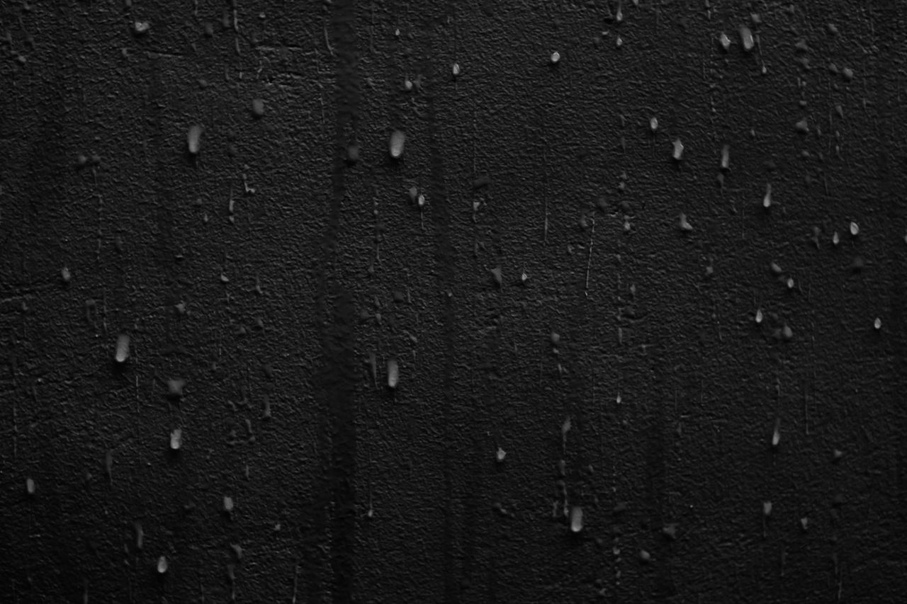 close up view of rain droplets on a cracked dark wall creating a moody