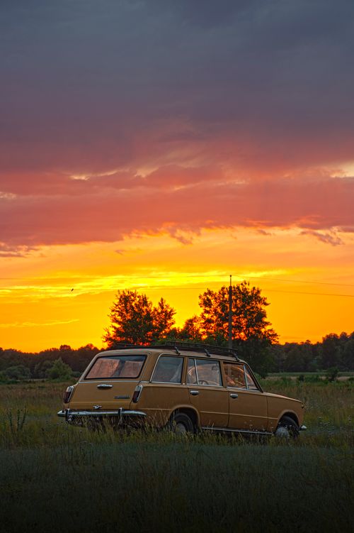 Free A classic vintage car parked in a grassy field during a stunning Kyiv sunset, capturing the beauty of nature and nostalgia. Stock Photo
