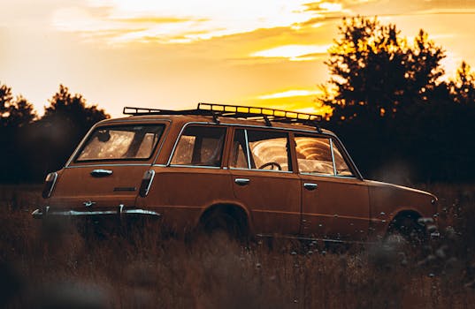 Retro yellow wagon car parked in a picturesque field during a vibrant sunset in Kyiv, Ukraine.