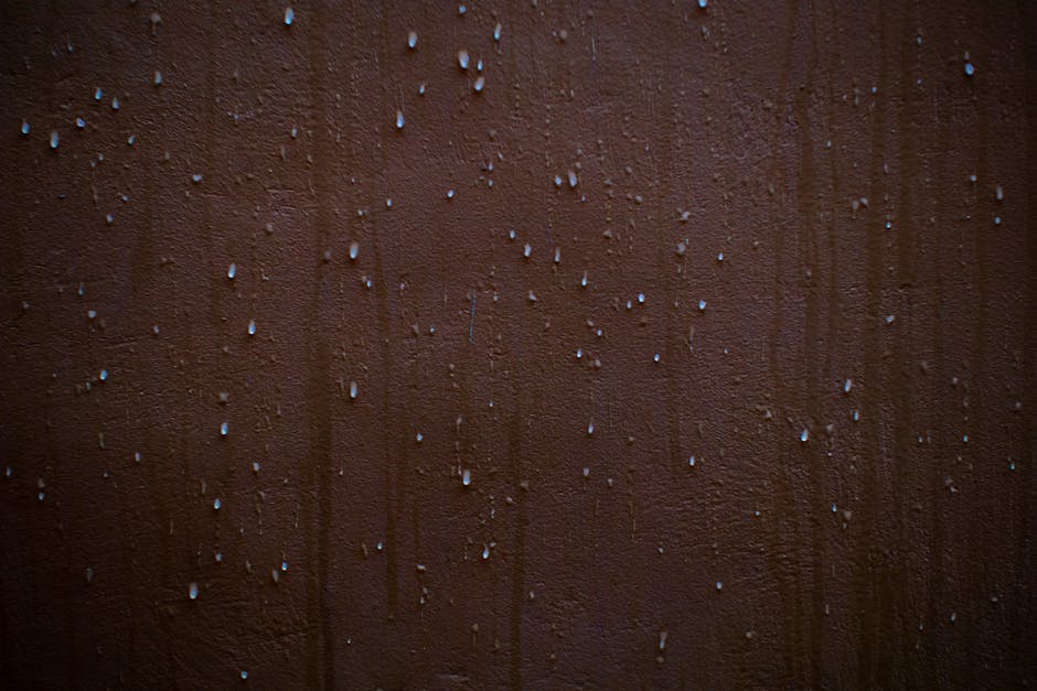 Detailed view of water droplets creating a texture on a brown wall surface.
