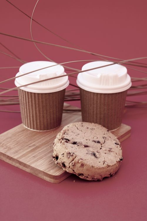 Free Creative display of coffee cups and a cookie on a wooden board against a pink backdrop. Stock Photo