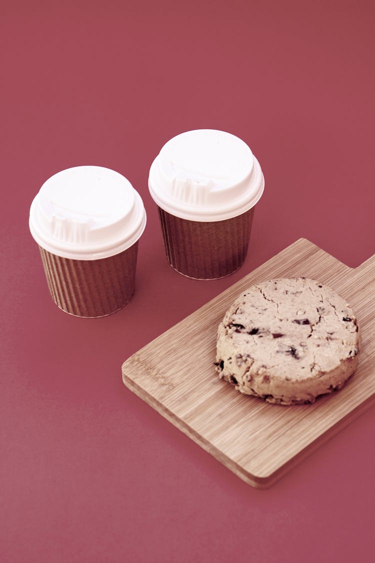 Cups Of Takeout Coffee And Cookie On Wooden Cutting Board