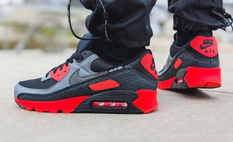 A Person Wearing Black And Red Air Max 90's