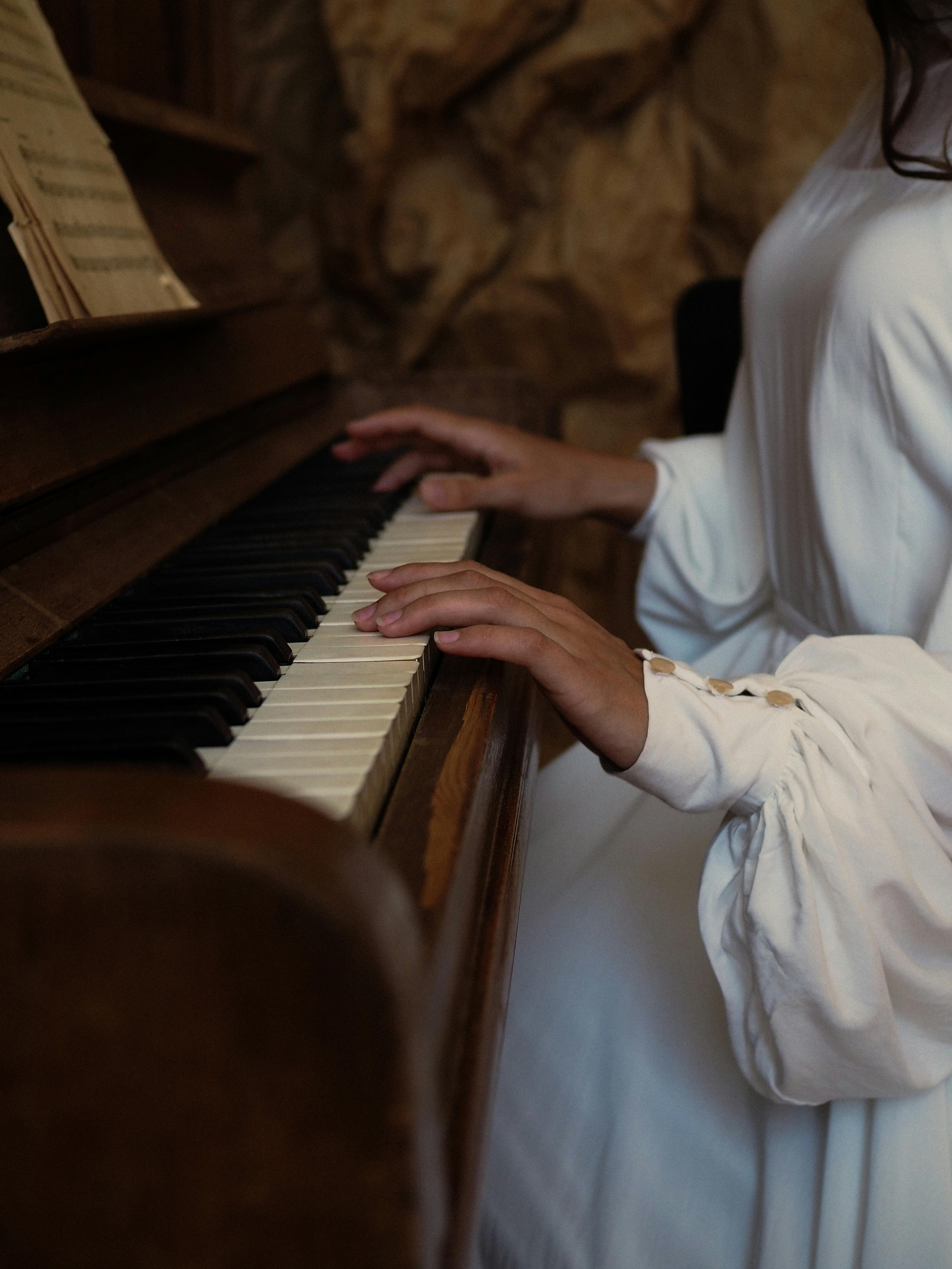 A woman elegantly playing a piano indoors, showcasing musical artistry and elegance.