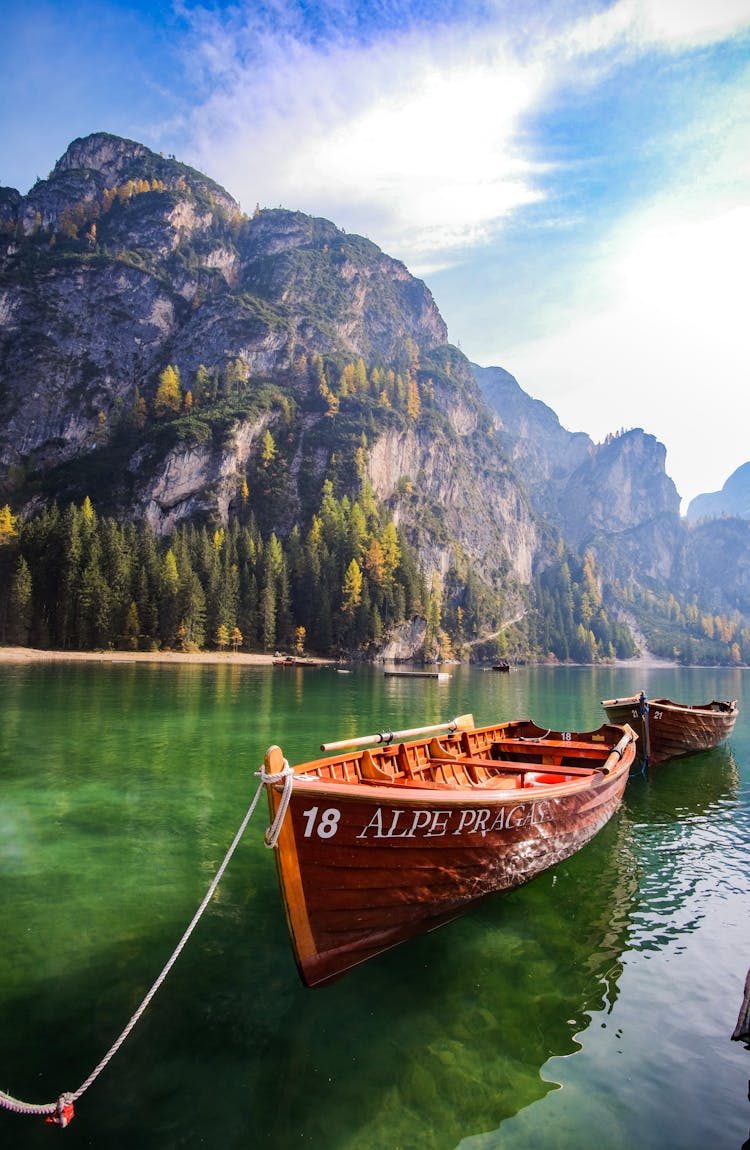 Wooden Rowboat Docked In Clear Alpine Lake