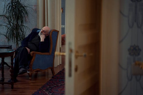 A Sad Man Sitting on Armchair