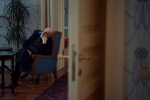 Free Elderly man sits pensively in an armchair in a warmly decorated room, conveying solitude. Stock Photo