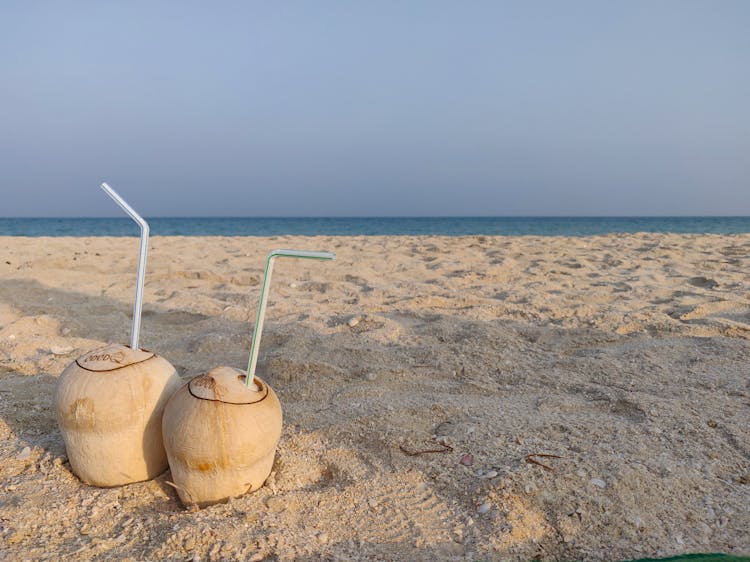 Coconuts With Straws On A Beach