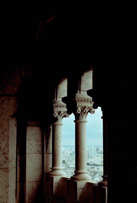 Majestic ancient stone pillars framing an urban cityscape bathed in moody light.