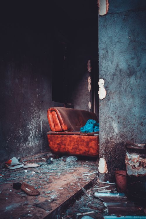 Free Explore an abandoned house with a broken sofa and debris strewn across the floor. Stock Photo
