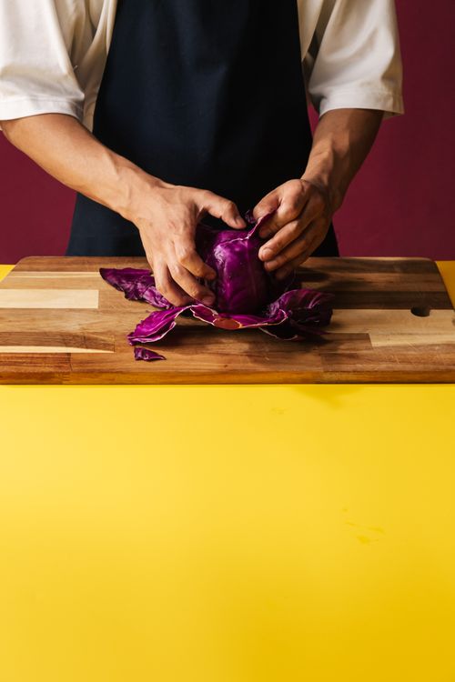 Free Chef's hands preparing red cabbage on a wooden chopping board. Stock Photo