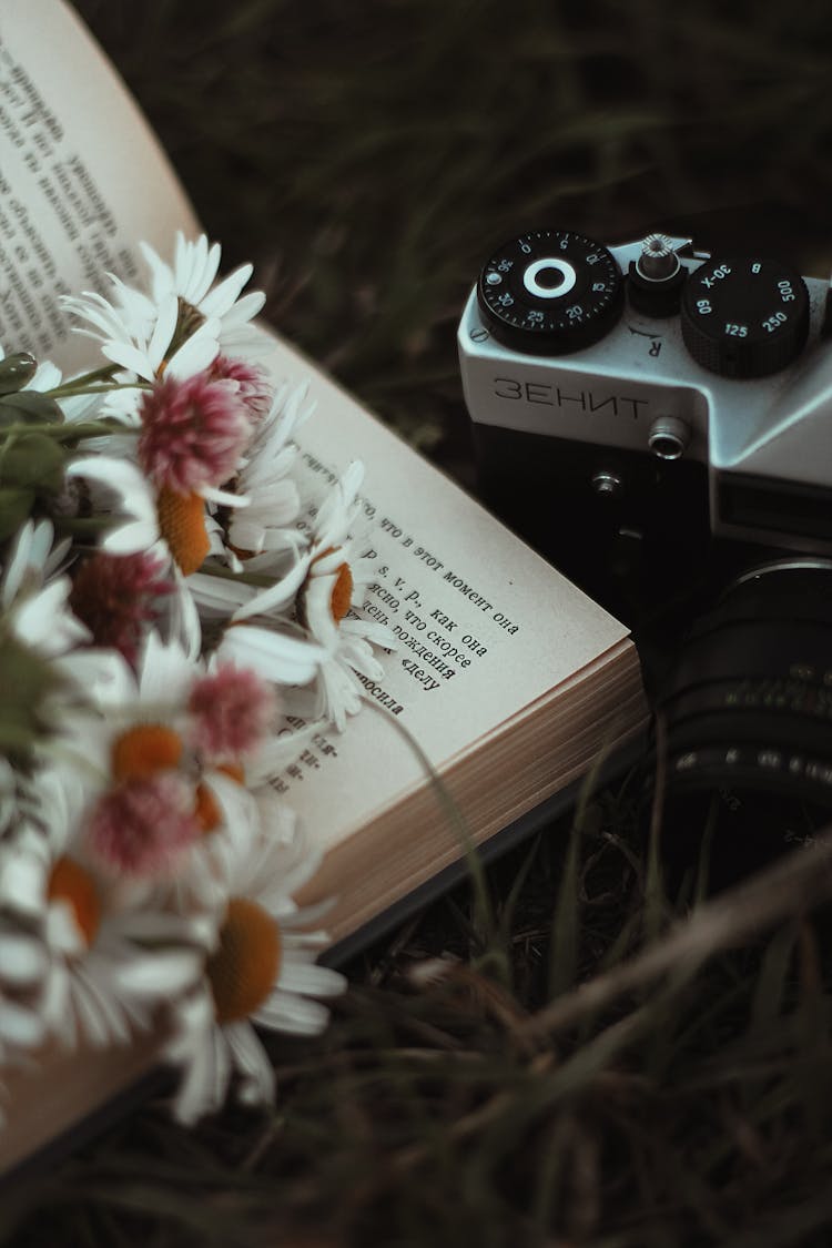 Flowers On Book Near Zenit Camera