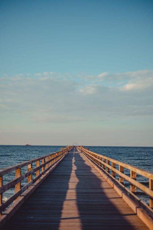Free A tranquil view of a pier extending into the sea under a clear sky, perfect for relaxation. Stock Photo