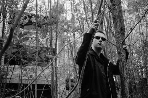 Grayscale Photo of Man Standing Near Trees