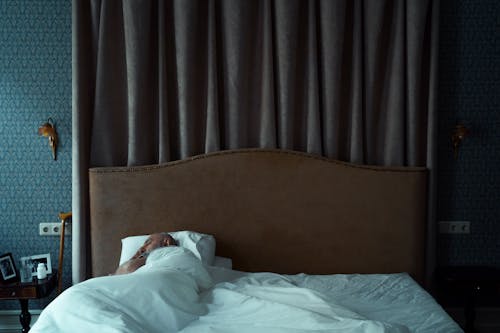 A Man Sleeping on the Bed while Using a White Blanket