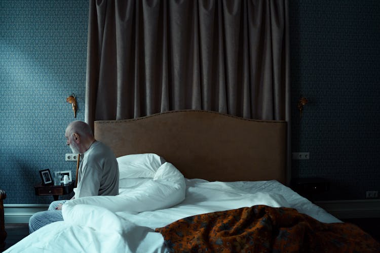 Photo Of An Elderly Man Sitting On A Bed