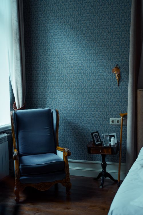 Free A cozy blue armchair in a tastefully decorated room with vintage elements. Stock Photo