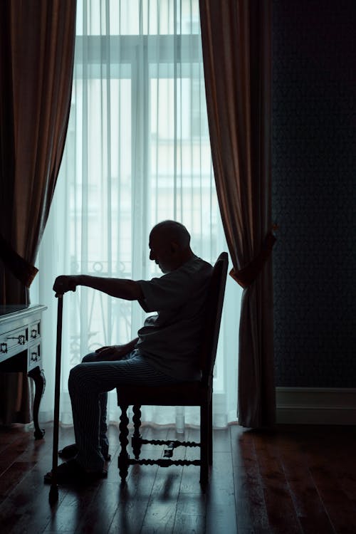 Free Silhouette of an Elderly Man sitting Alone in a Room  Stock Photo
