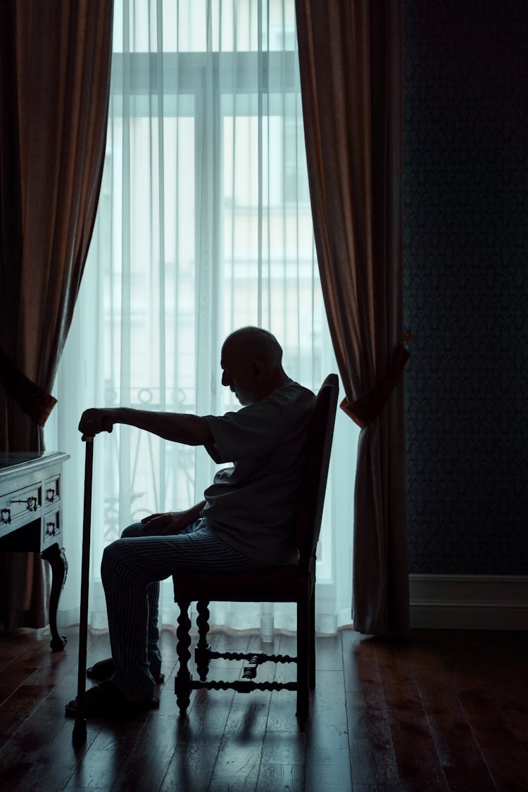 Silhouette Of An Elderly Man Sitting Alone In A Room 