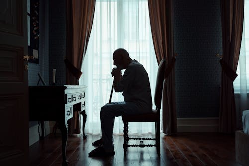 Silhouette of an Elderly Man sitting Alone in a Room