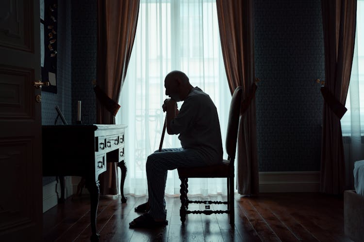 Silhouette Of An Elderly Man Sitting Alone In A Room