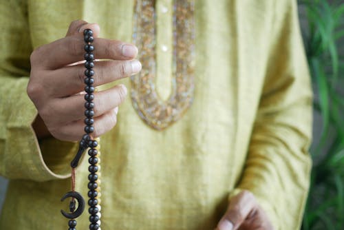 Free Hand of Muslim Person Praying Using Prayer Beads Stock Photo