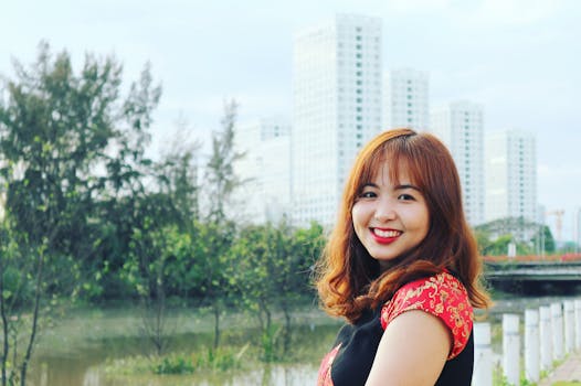 一位穿着传统服装的快乐女人在公园里微笑，公园靠近城市建筑