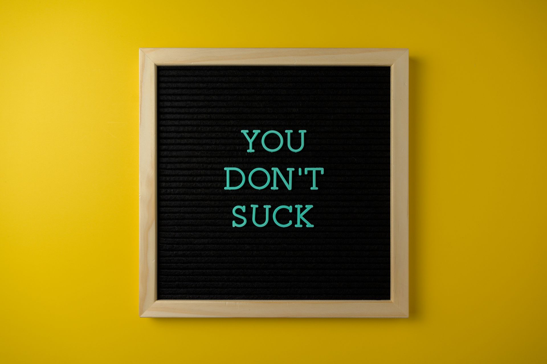 Simple blackboard sign displaying an uplifting message against a vibrant yellow backdrop.