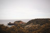 A breathtaking view of a rocky coastline and a distant island under a clear sky.