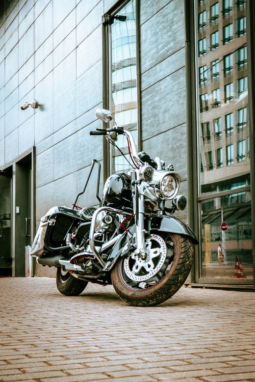 Free Sleek chrome motorcycle parked beside modern building in urban city setting, showcasing design and style. Stock Photo