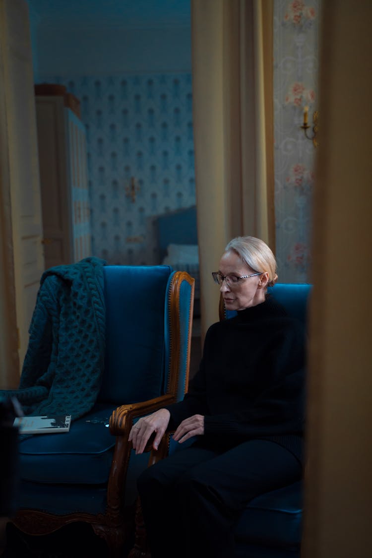 An Elderly Woman In Black Sweater Sitting On The Chair