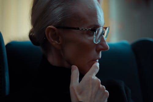 Close-up Shot of Woman in Eyeglasses in Deep Thoughts