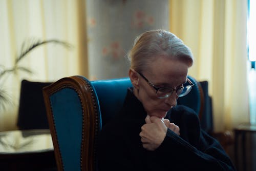 Elderly Woman in Black Dress Sitting on Blue Wooden Armchair