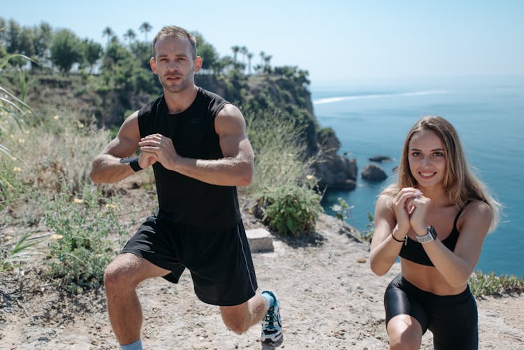 A Couple Exercising On The Mountain Peak While Smiling At The Camera