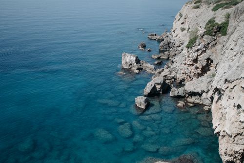 Free A breathtaking aerial view of a rugged coastline with clear blue waters and rocky cliffs. Stock Photo