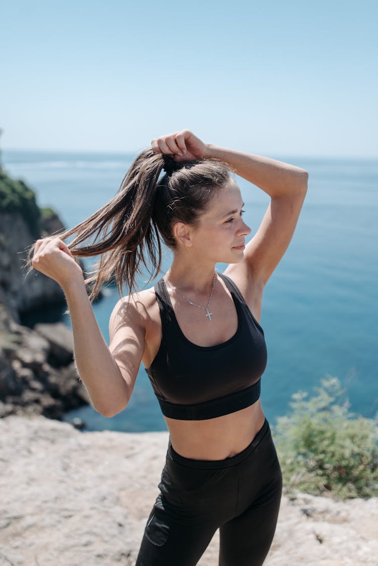 A Beautiful Woman In Black Sports Bra Holding Her Hair