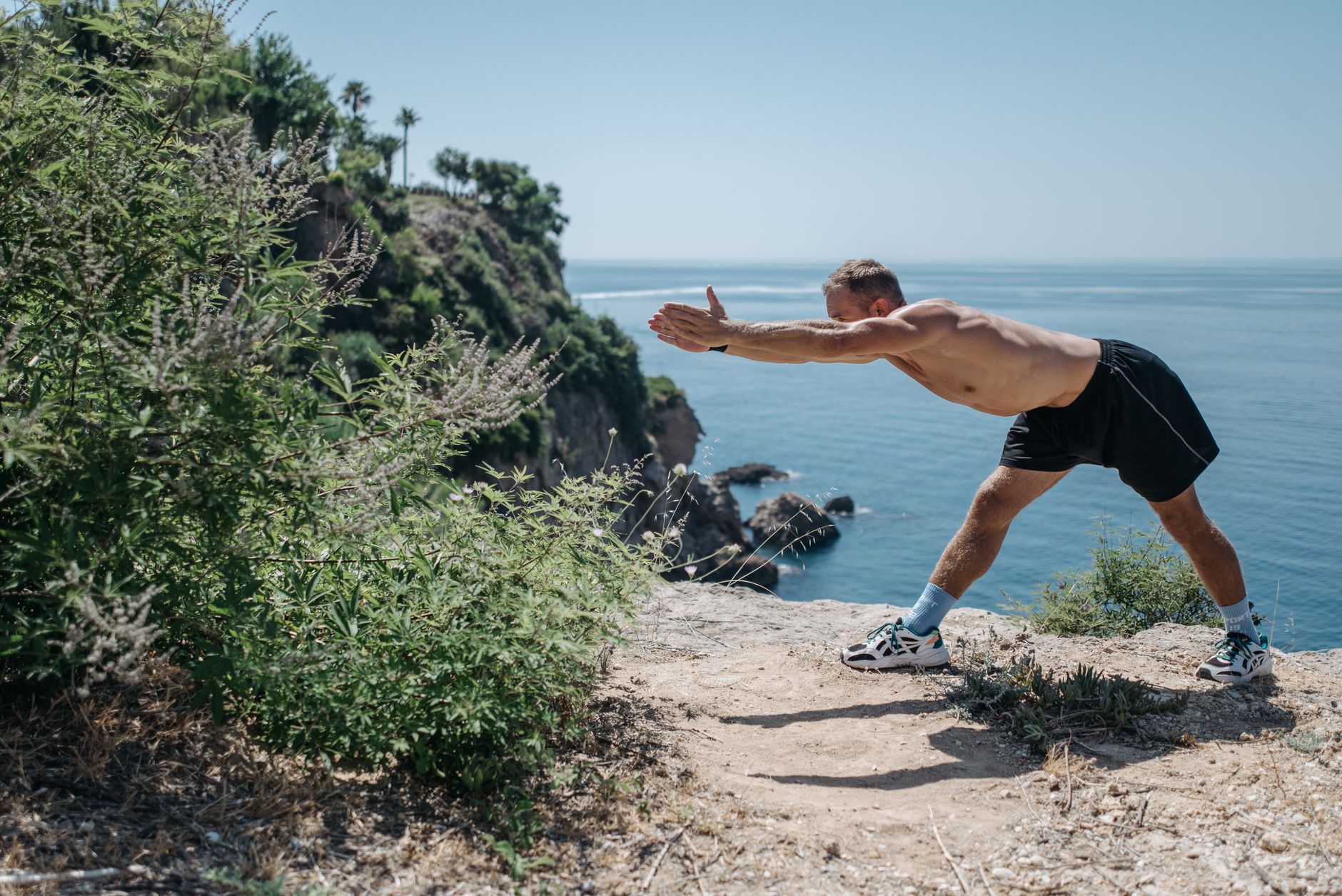 fenbendazole dosing for prostate cancer support — A shirtless man performs stretching exercises on a scenic cliff overlooking the ocean.